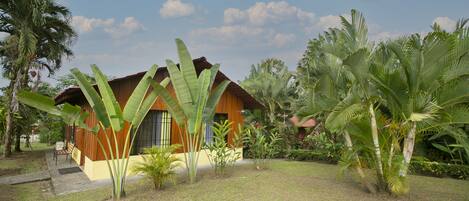Una casa de madera con techo inclinado rodeada de exuberante vegetación tropical.