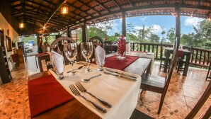 Un espace repas avec des tables dressées pour le service, où l’on peut admirer de la belle verrerie et des couverts élégants.