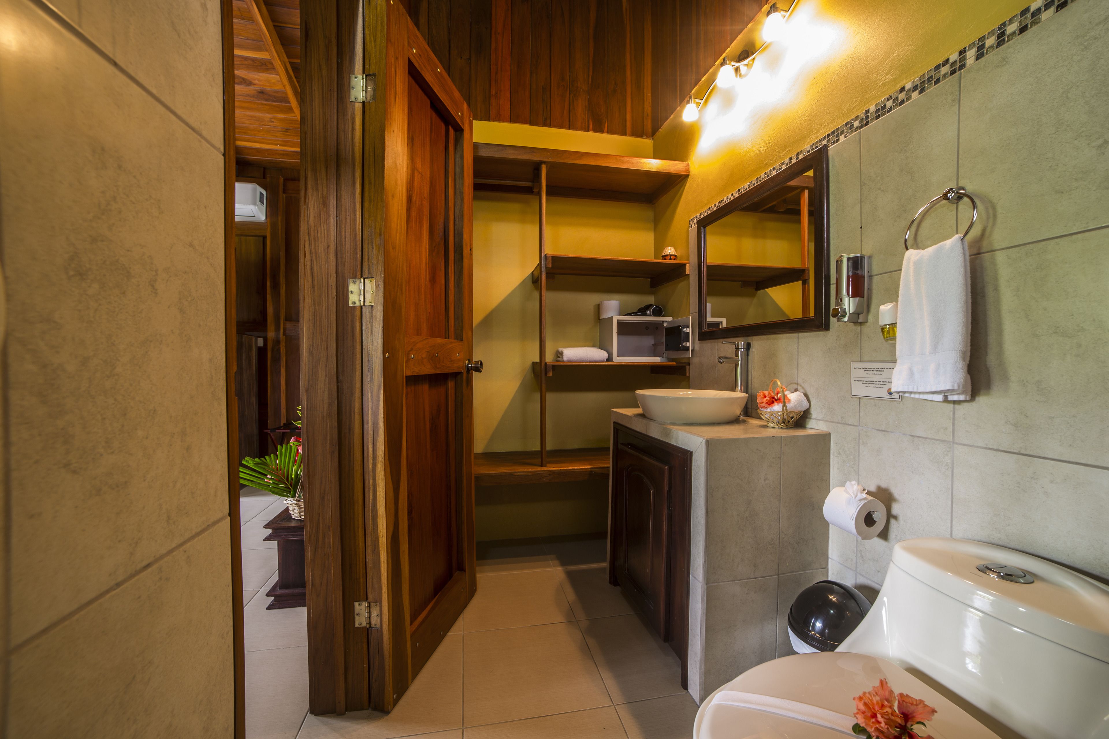 A compact bathroom with a wooden door, a sink, a toilet, and a mirror.