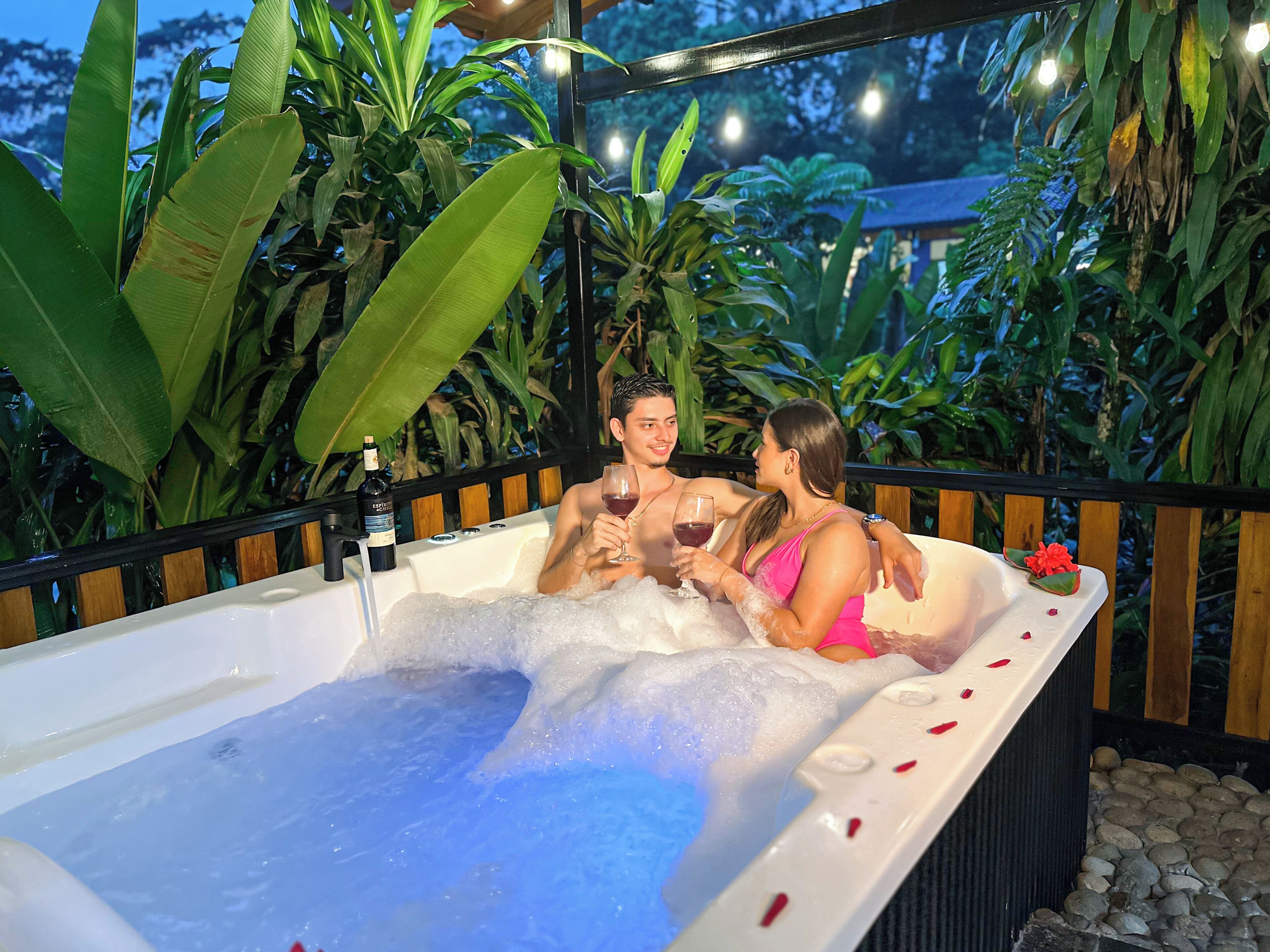 Un bain à remous doté d’une terrasse en bois et entouré de plantes tropicales.