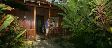 A wooden building with a tiled roof, surrounded by lush greenery.