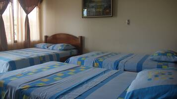 A room with two beds, each with blue and white bedding and a wooden headboard.