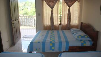 A room with two beds, a balcony, and a door leading outside.