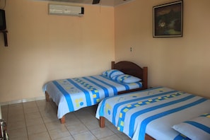 Una habitación con dos camas, paredes color beige y un cuadro en la pared.