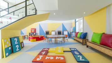 Een speelruimte voor kinderen met een trap, kleurrijke spekmatten en zitplaatsen.