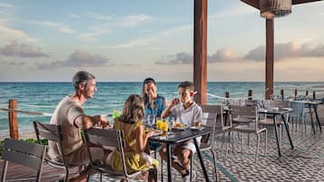 A group of people dining at an outdoor table with a view of the ocean.