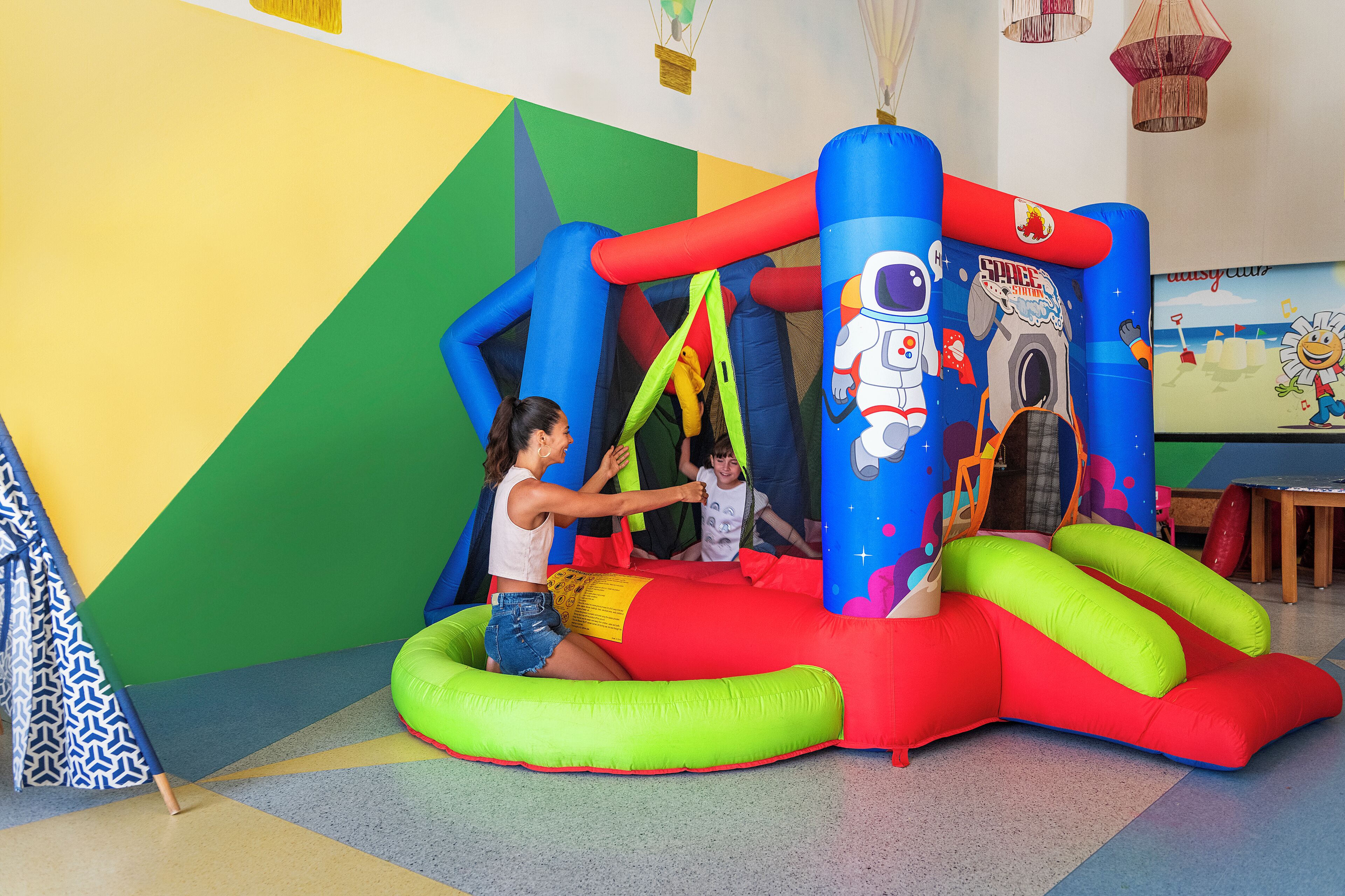 A colorful inflatable play area with a space theme, including a rocket and astronaut figure.