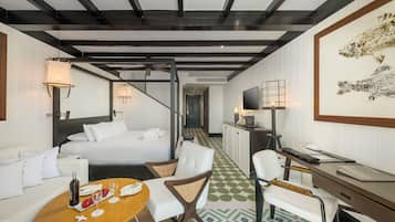 Een hotelkamer met een bed, een bureau, een stoel, een tafel met een fles en glazen, en een televisietoestel.