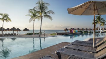 Relax by the pool surrounded by palm trees and lounge chairs.