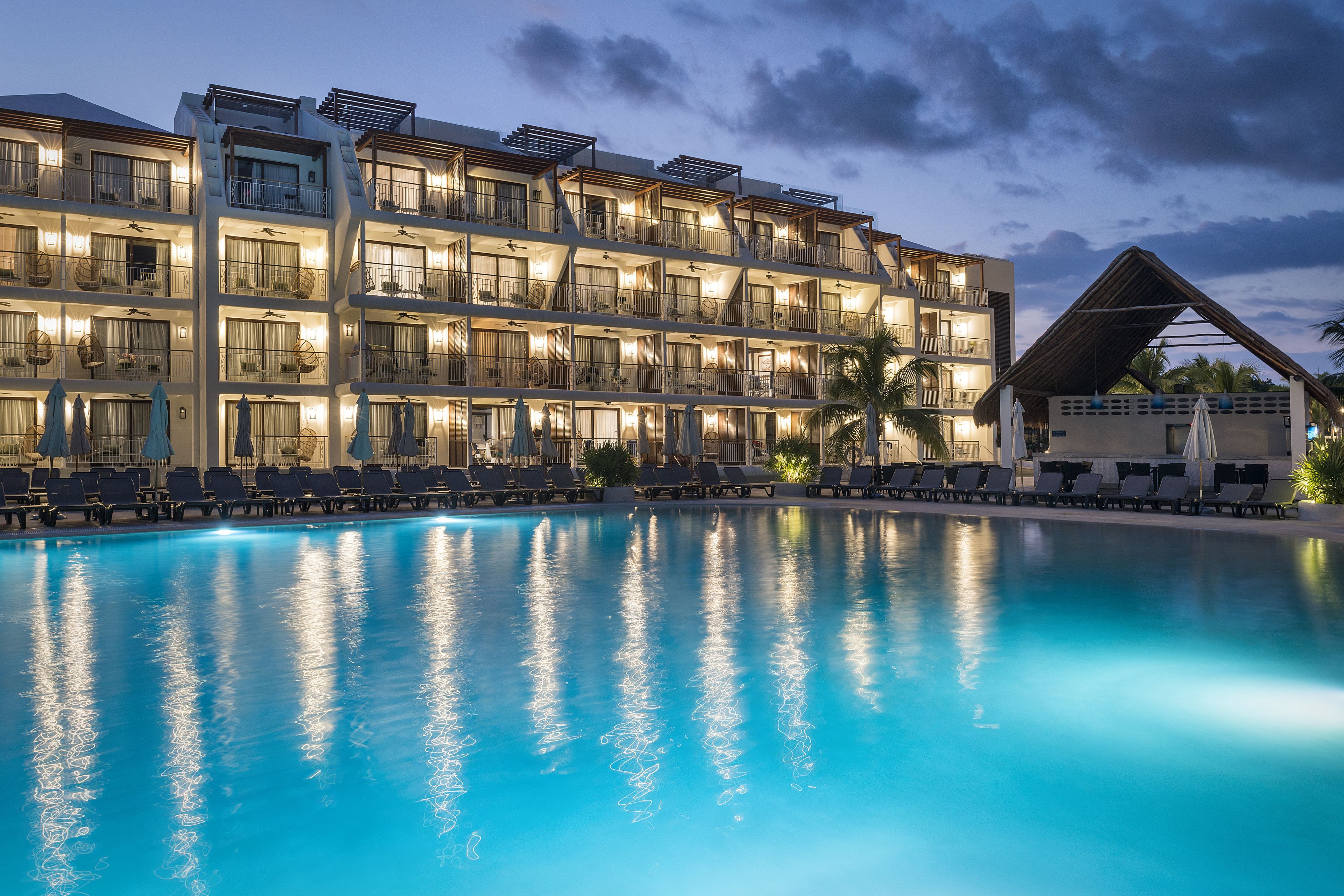 A hotel with a pool, multiple balconies, and sun loungers.