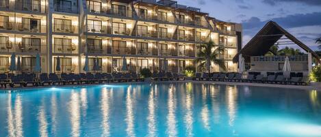 A hotel with a pool, multiple balconies, and sun loungers.
