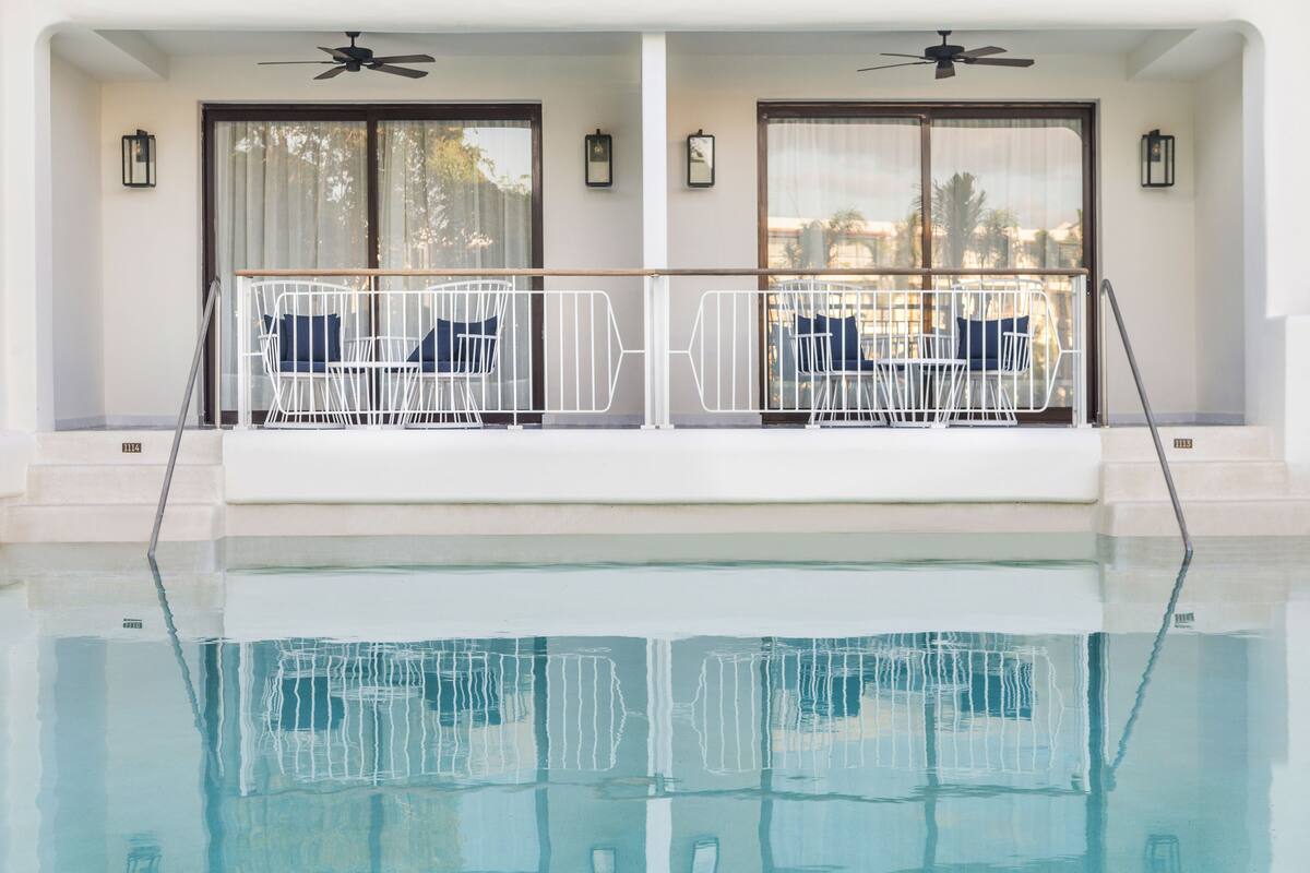 A poolside area with two sun loungers, a ceiling fan, and a view of the pool.