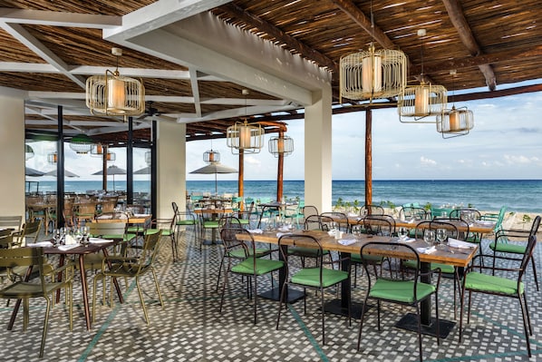 An outdoor dining area with tables and chairs, overlooking the sea. - El Beso Adults Only at Ocean Riviera Paradise - All Inclusive (Playa del Carmen)