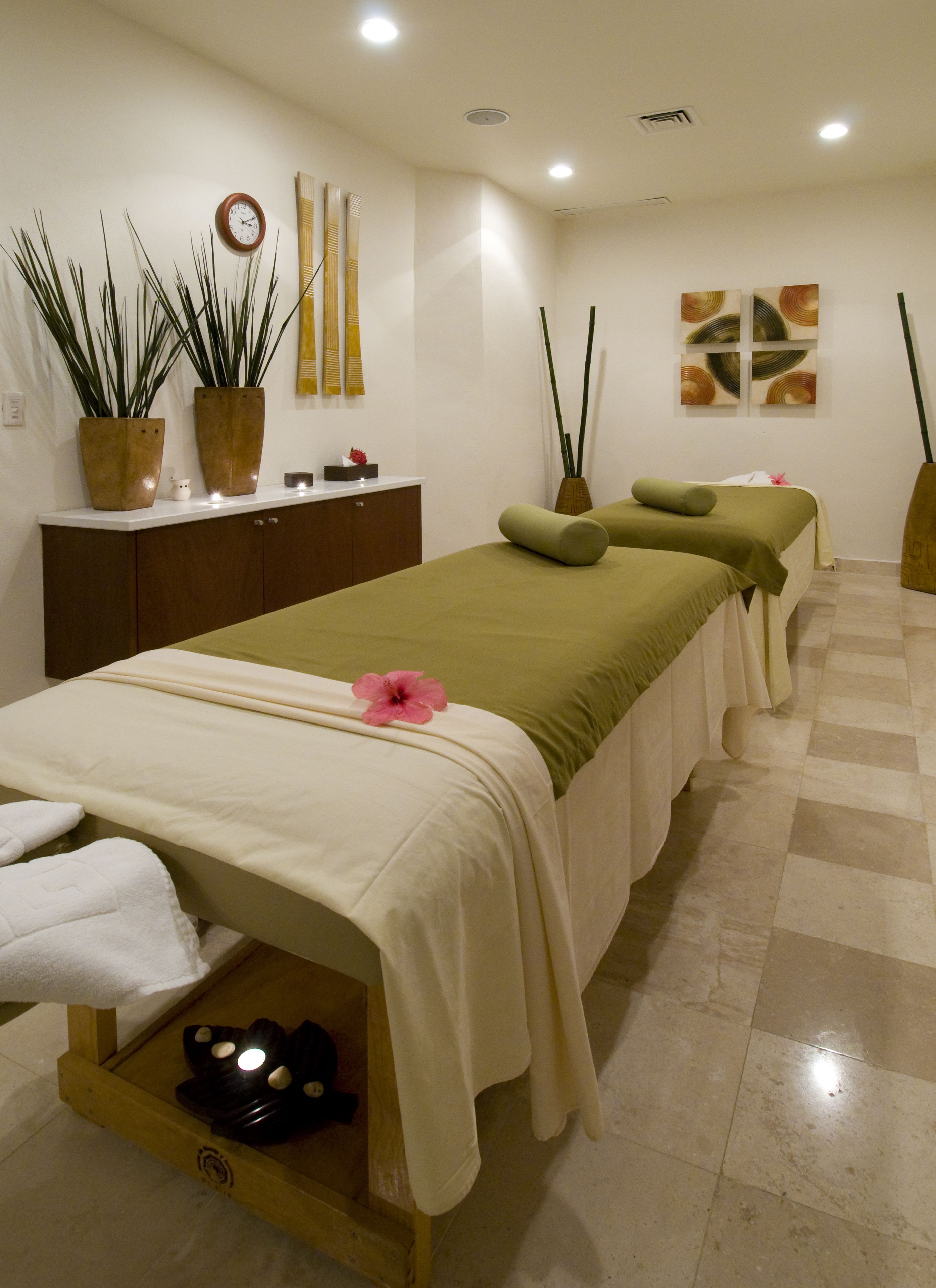 Un salón de spa con tres camillas de masaje, un mostrador de recepción y plantas en macetas.