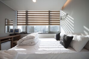 Ein Hotelzimmer mit Bett, Schreibtisch und einem Fenster mit Jalousien.