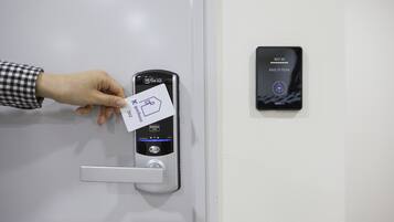 A hand inserting a card into a card reader on a door, with a keypad and a 'KEY IN' sign above it.