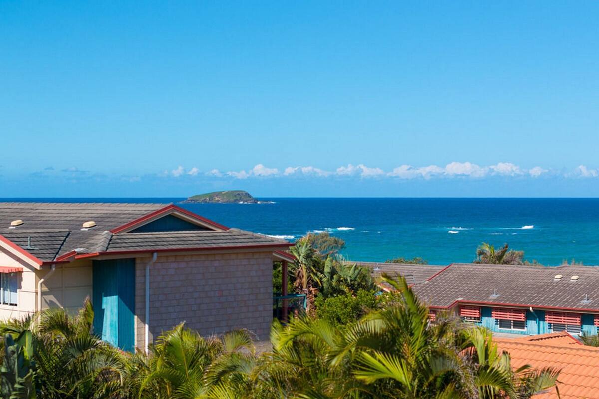 A coastal building with a view of the ocean and a small island in the distance.