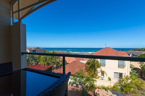 A balcony with a view of a coastal area, including houses and palm trees. - Beach Haven Executive Apartments (Korora)