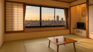 A traditional Japanese room with tatami flooring, a sliding shoji screen, a television, and a table with two cups. - City Hotel Airport in Prince (Izumisano)