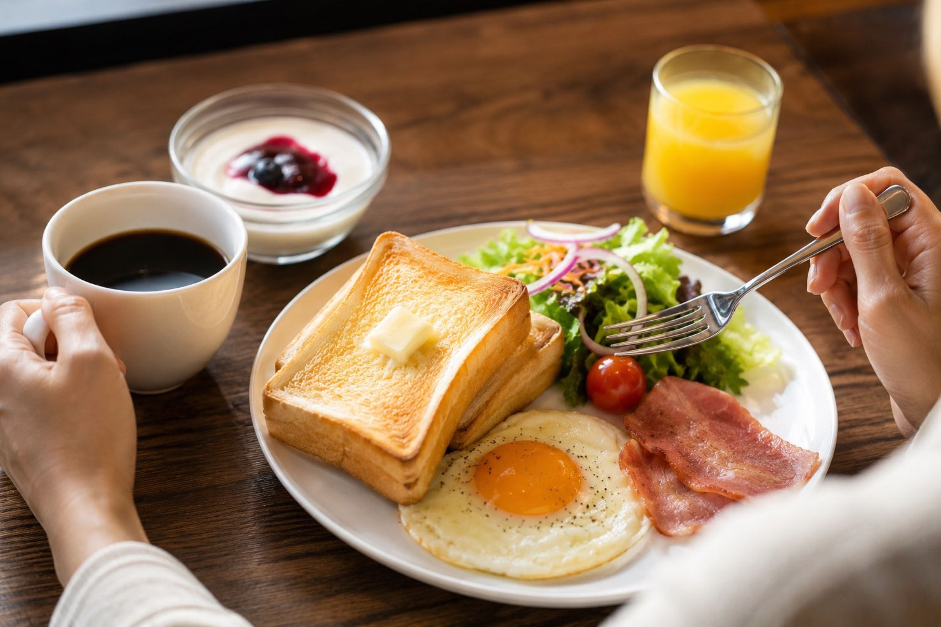A breakfast plate with toast, eggs, bacon, and a salad, accompanied by a glass of orange juice and a cup of coffee.