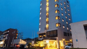A hotel with a modern design, featuring multiple balconies and a well-lit entrance. - City Hotel Airport in Prince (Izumisano)