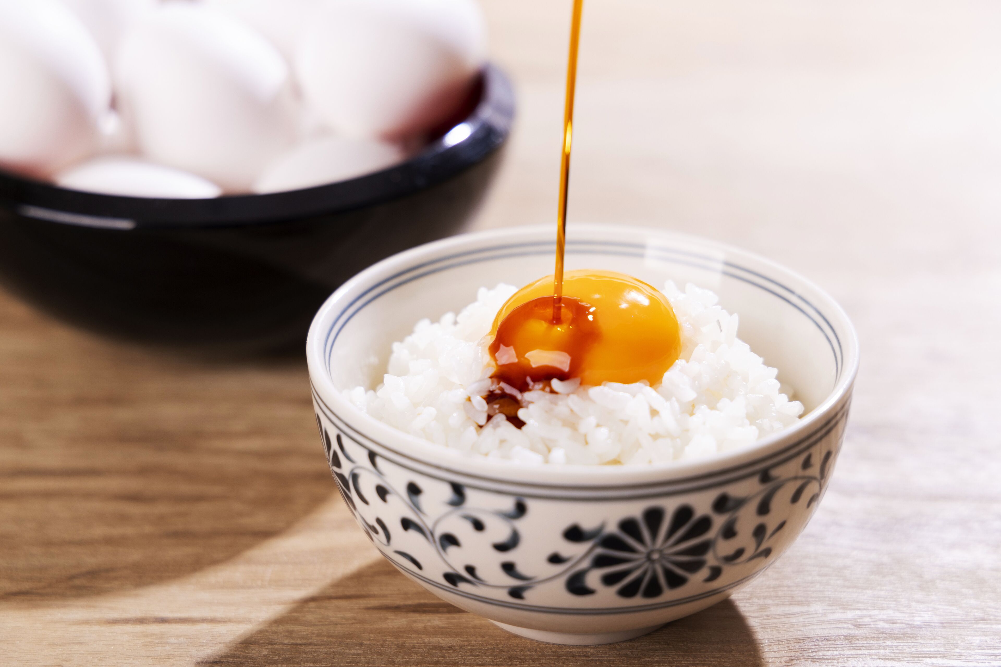 A bowl of white rice with a dollop of sauce and a raw egg yolk on top.