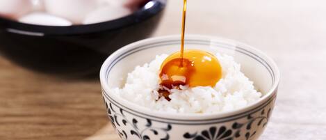 A bowl of white rice with a dollop of sauce and a raw egg yolk on top.