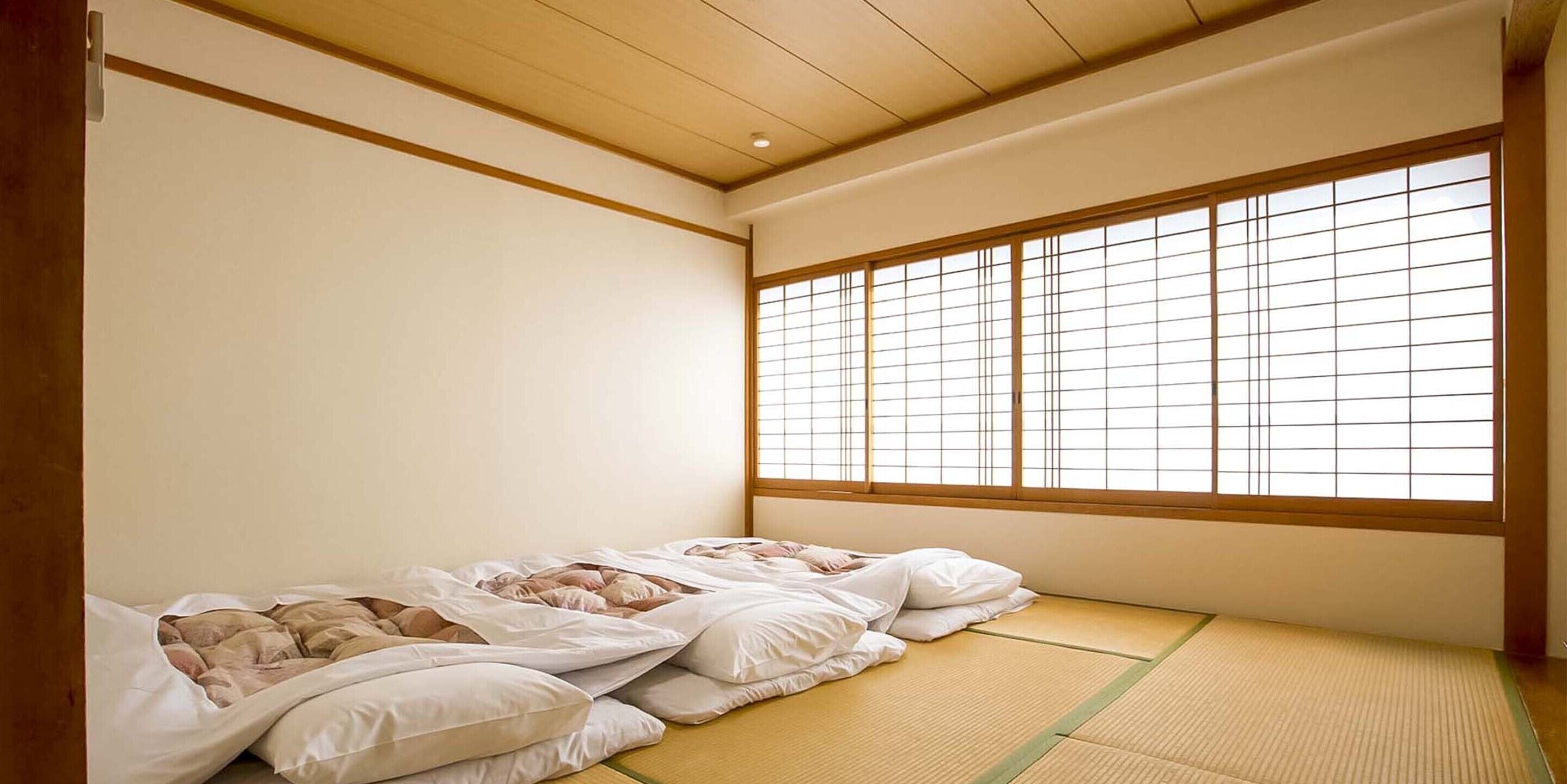 Perinteinen japanilainen huone, jossa on tatamimatto, matala puukatto ja suuri shoji-tyylinen ikkuna.