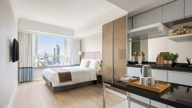 Ein modernes Hotelzimmer mit einem großen Bett, einem Essbereich und Blick auf die Stadtlandschaft.