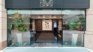 Der Eingang eines Hotels mit Glasfassade, einer Rezeption und einem modernen Innenraum.