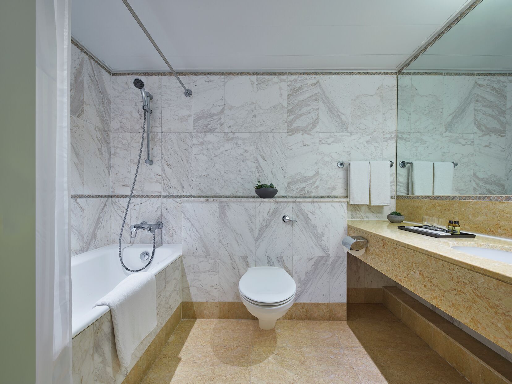 A bathroom with a bathtub, toilet, and a sink with a mirror.