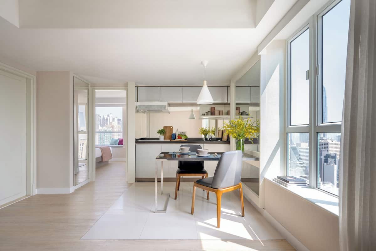 A modern kitchen with a dining area, large windows, and a city view.