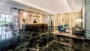 Eine moderne Hotelhalle mit einer Rezeption, einer Sitzecke und großen Fenstern.