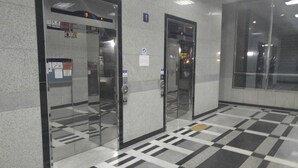An elevator with a digital display, a wheelchair accessibility sign, and a tiled floor pattern. - Justin House (Seoul)