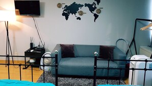 A bedroom with a bed, a world map on the wall, a TV, a lamp, and a heater. - Justin House (Seoul)