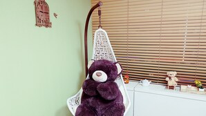 A room with a hanging chair, a white cabinet, and a teddy bear. - Justin House (Seoul)