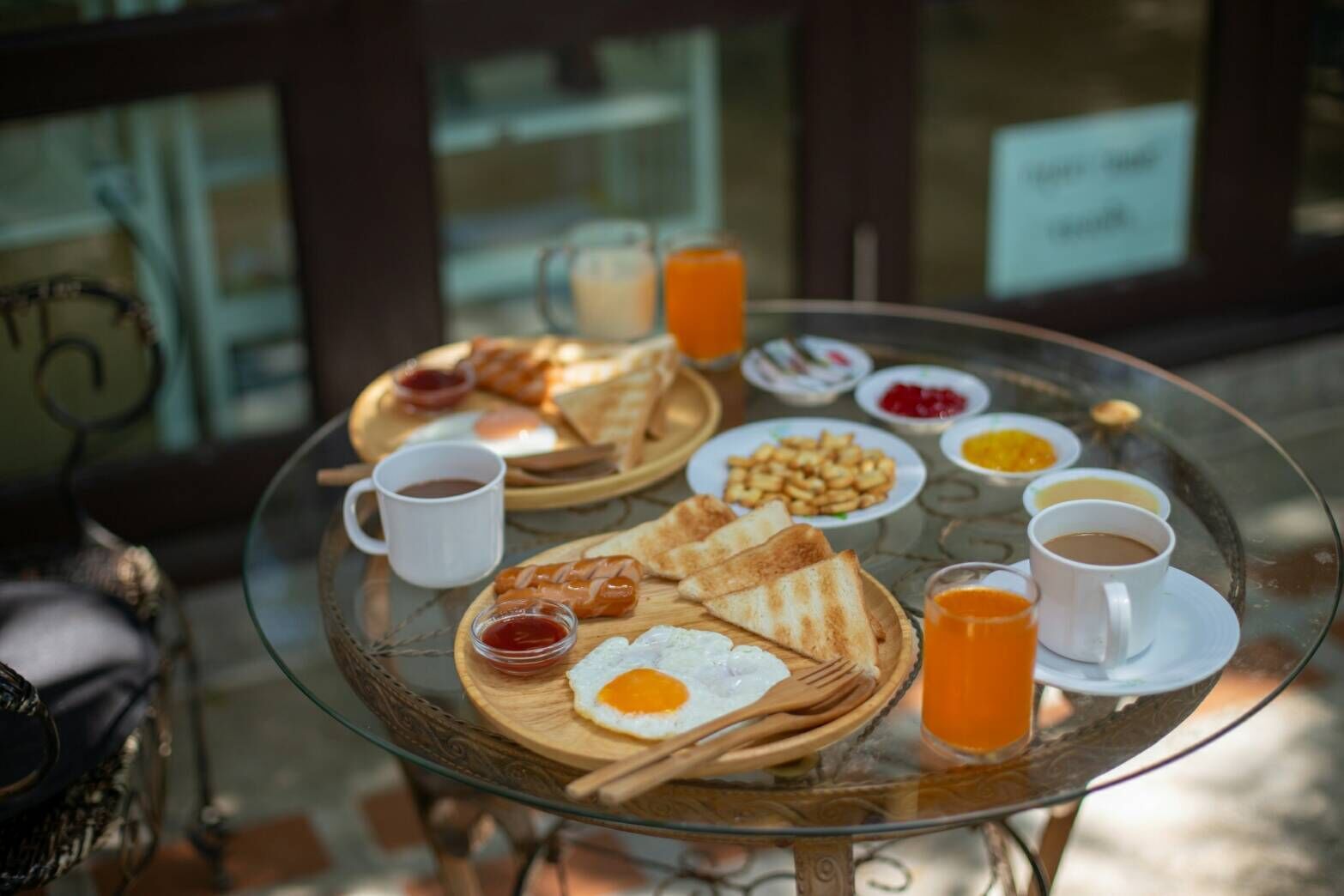 A breakfast setting with toast, eggs, and beverages on a glass table.