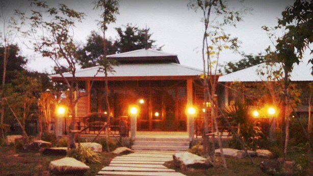 A pathway leading to a building with a covered entrance and multiple lights.