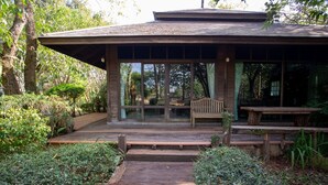 A wooden structure with a bench and a table, surrounded by greenery.