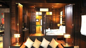 A cozy room with a sofa, two bedside tables with lamps, a bed, and a wooden wall with a mirror.
