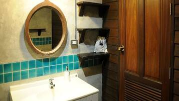 Une salle de bain avec un lavabo blanc, un miroir rond et des étagères en bois.