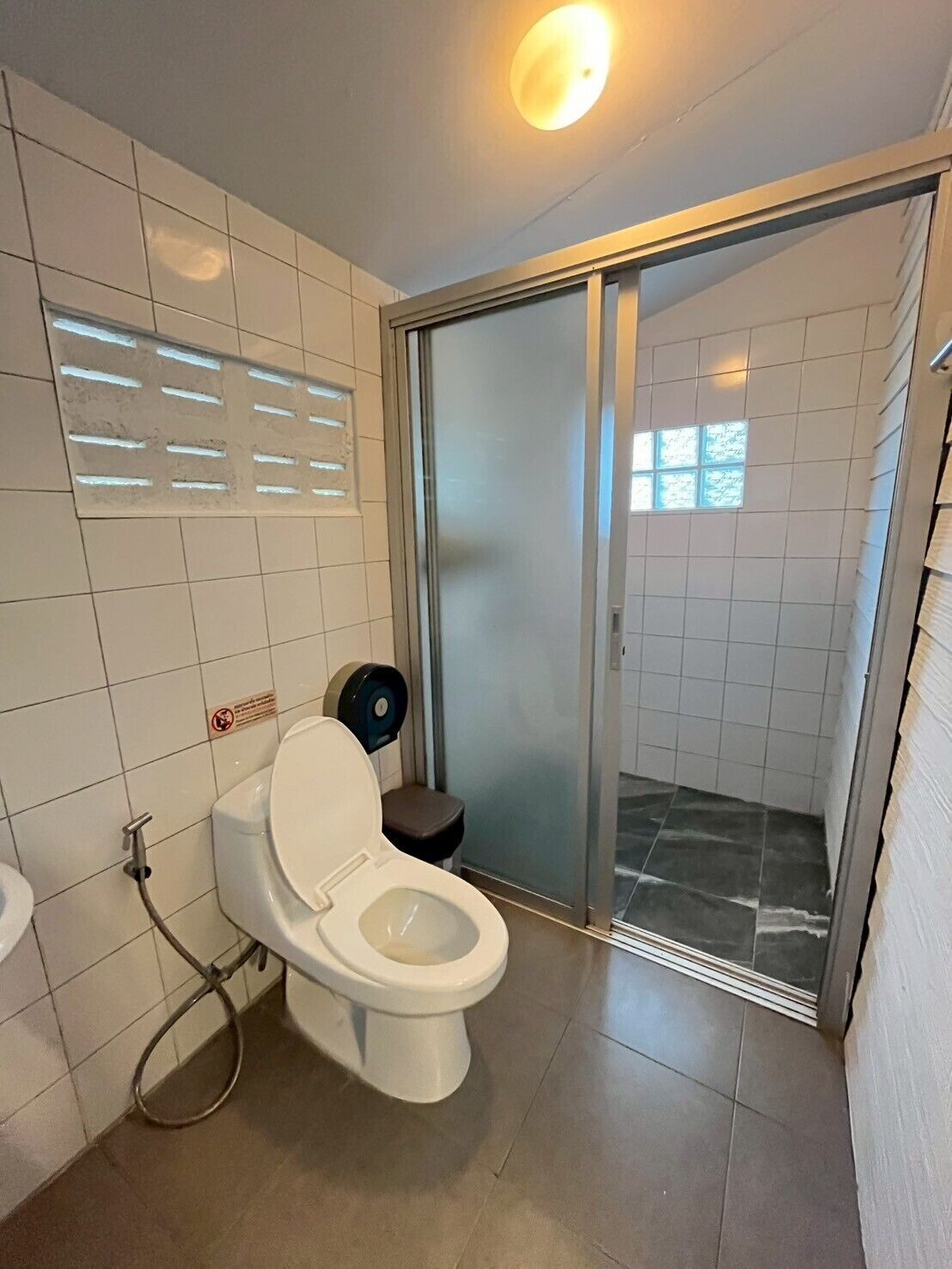 A modern bathroom with a toilet, bidet, and a glass shower enclosure.