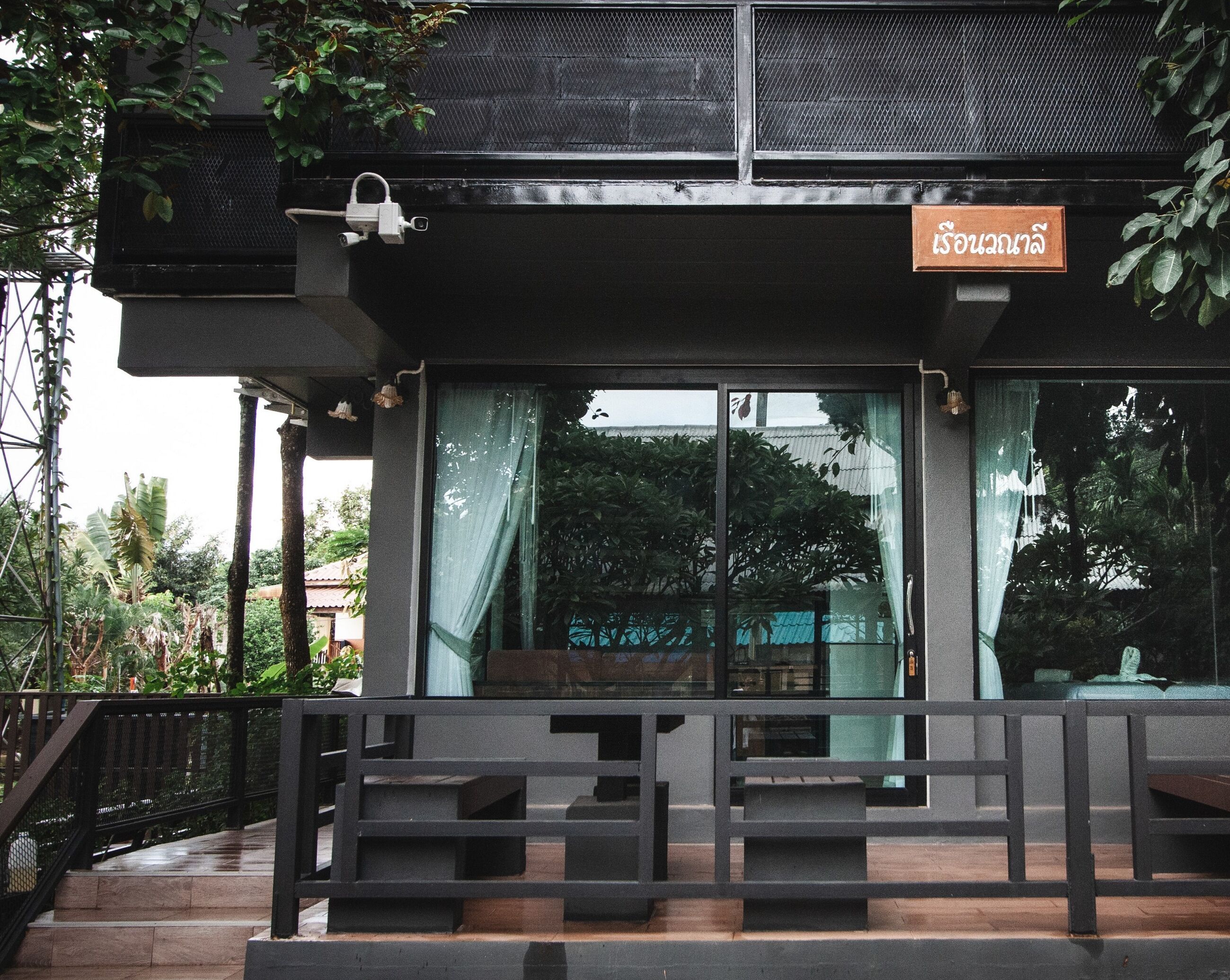 A modern building with a sign in a foreign language, large windows, and a staircase leading to an upper level.