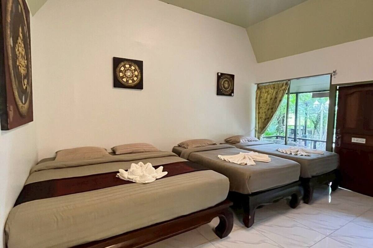 Habitación de hotel con dos camas, un candelabro y una ventana con cortinas.