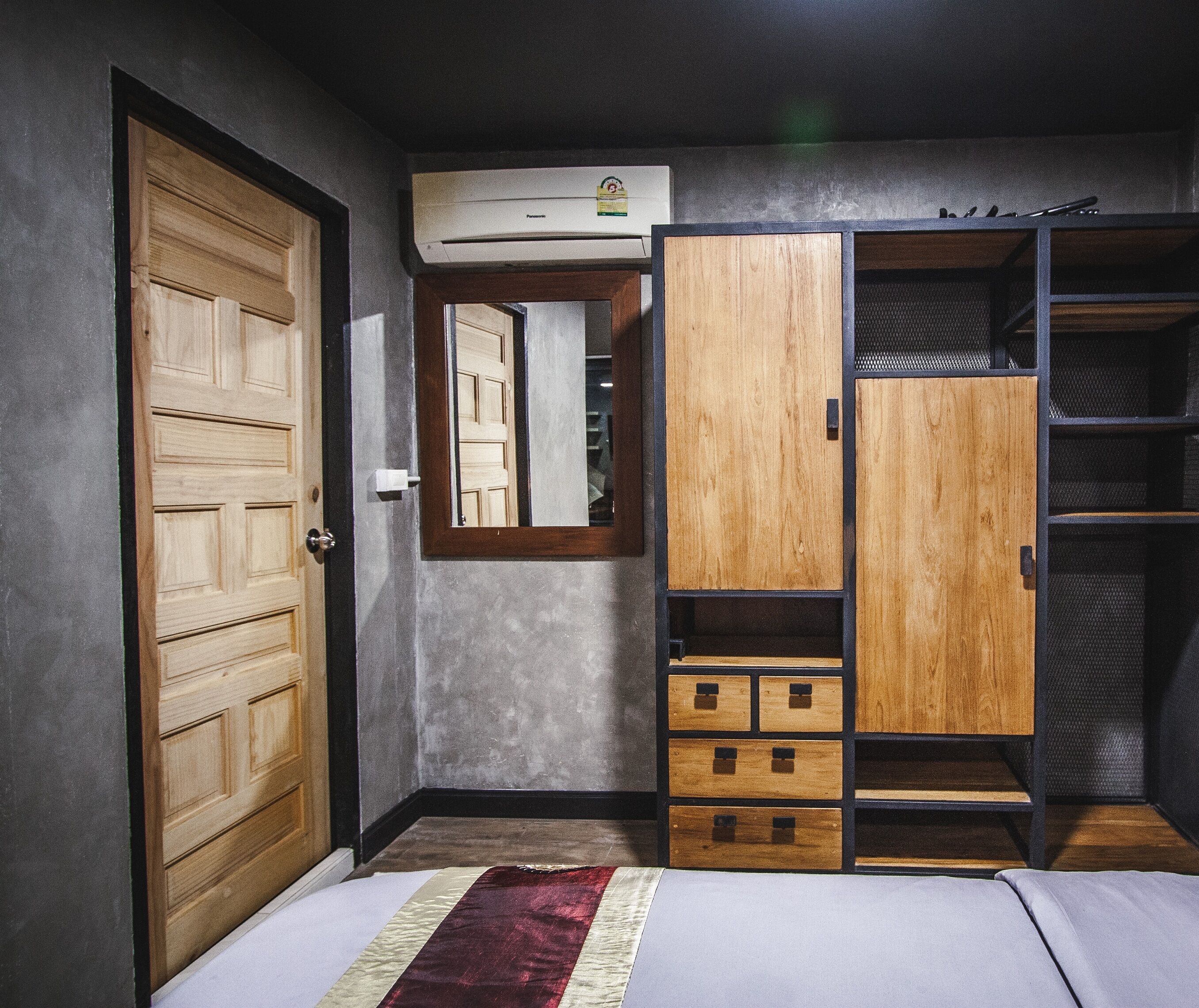 Un dormitorio con un armario de madera, un espejo y una cama.