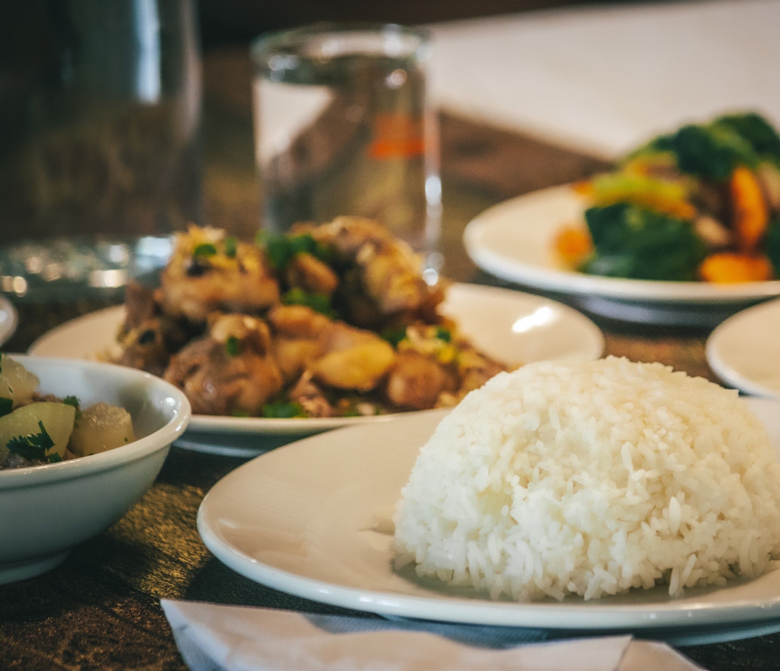 A table with plates of food including rice, chicken, and vegetables.