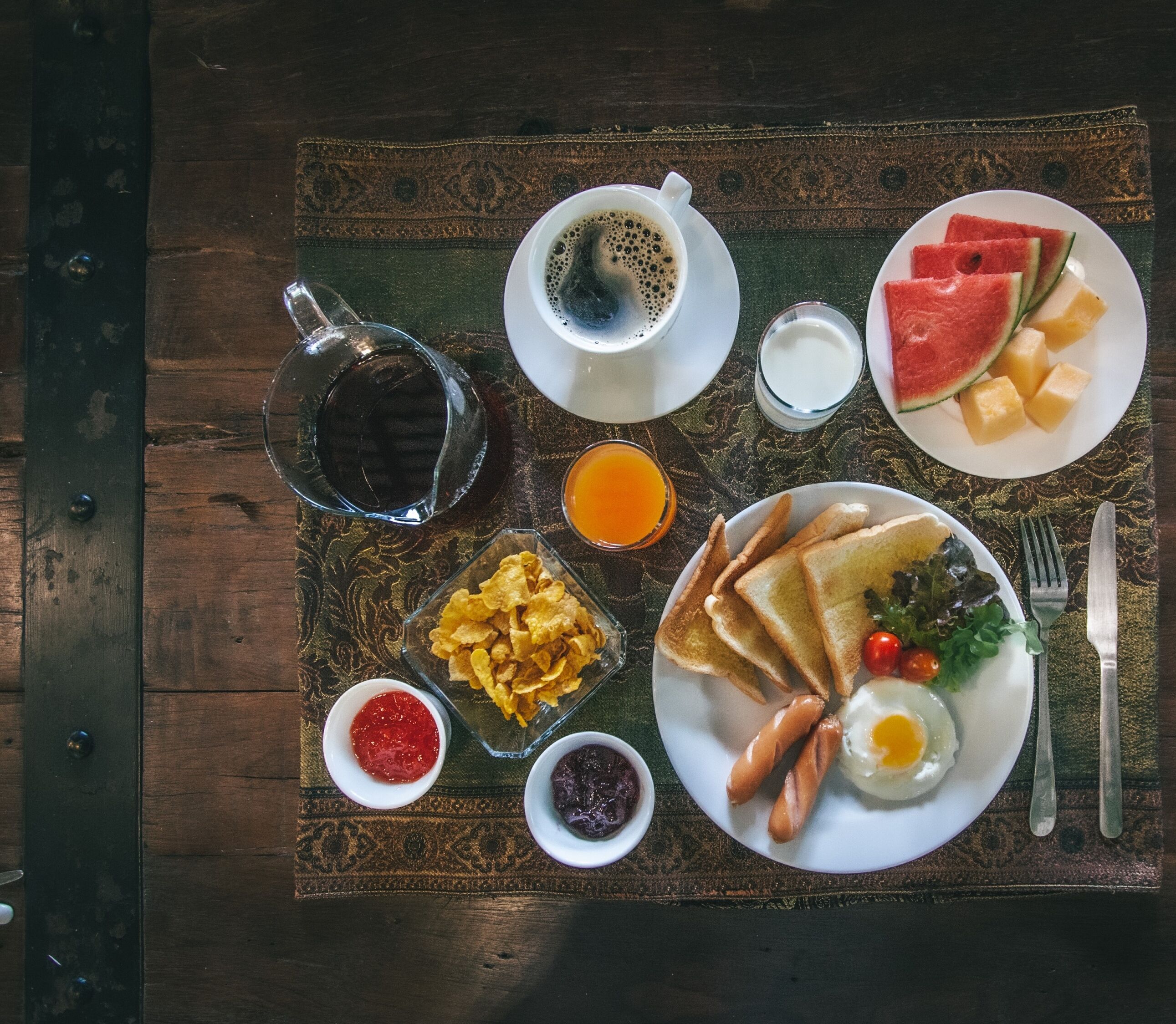 A breakfast tray with toast, sausages, eggs, and various condiments.