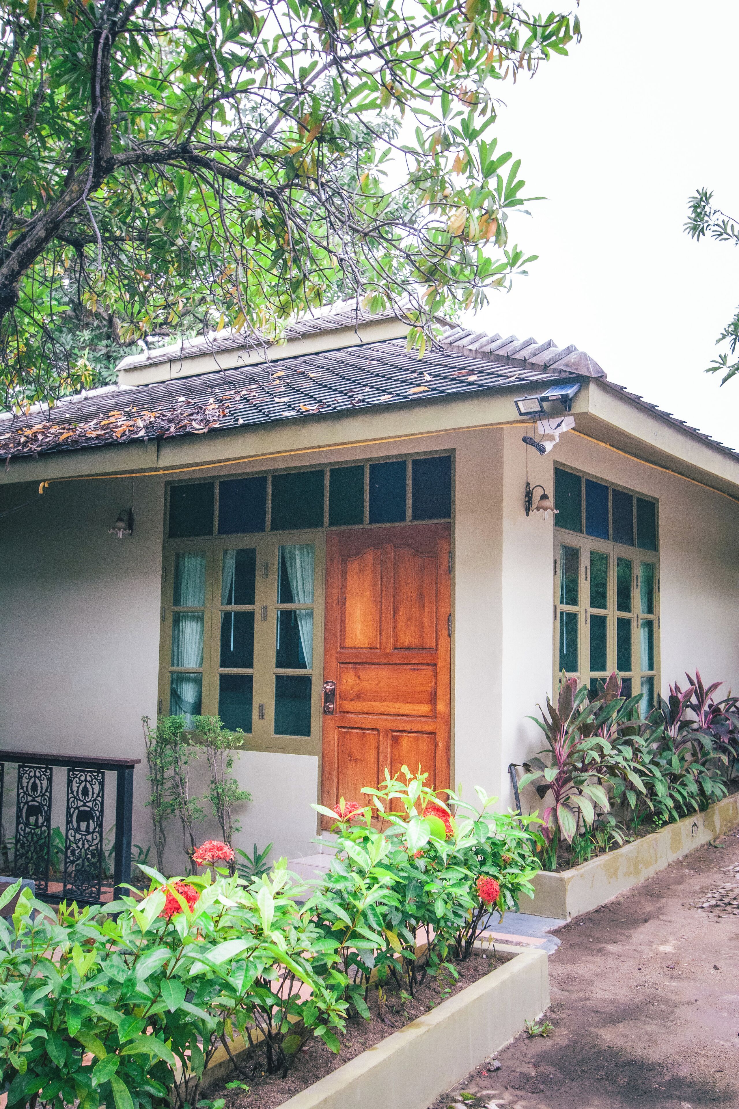 Una casa con puerta de madera, ventanas amplias y techo de tejas.