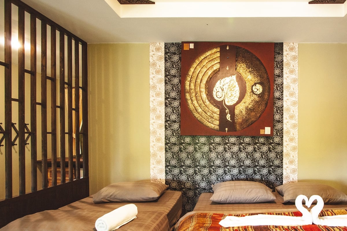 Una habitación de hotel con dos camas, un adorno en la pared y una cortina estampada.