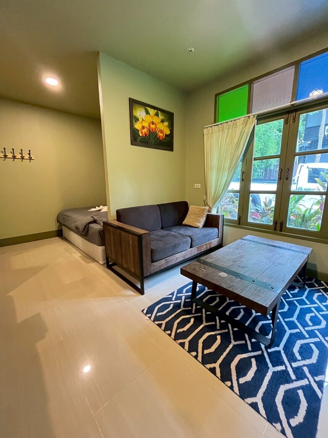 A living room with a sofa, a coffee table, a painting, and a window with curtains.